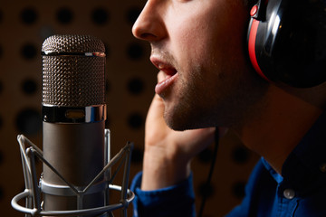 Naklejka premium Male Vocalist Singing Into Microphone In Recording Studio
