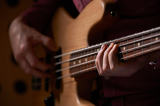 Close Up Of Bass Guitarist Playing Instrument