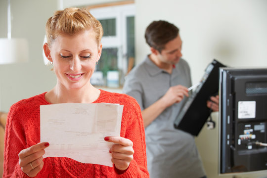 Happy Woman Looking At Bill For TV Installation
