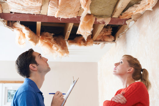 Builder And Client Inspecting Roof Damage