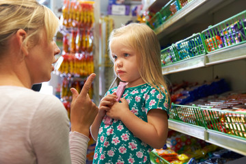 Girl Having Arguement With Mother At Candy Counter In Supermarke