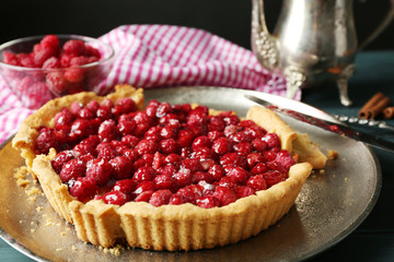 Tart with raspberries on tray, on wooden background