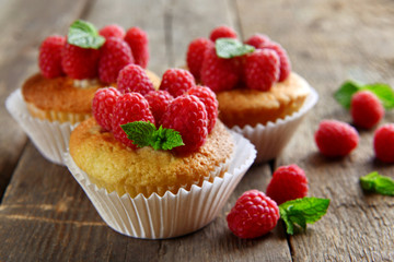 Delicious cupcakes with berries and fresh mint on wooden table close up