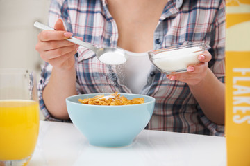 Teenage Girl Adding Sugar To Breakfast Cereal