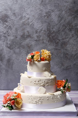 White wedding cake decorated with flowers on grey background