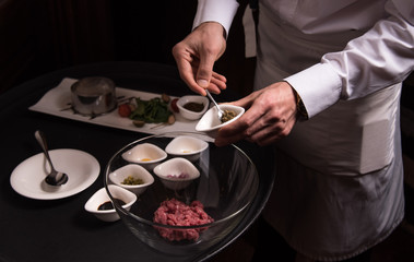 Chef prepares a delicious tartare, all the ingredients on the table next to
