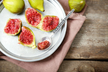 Ripe figs on tray, on wooden background