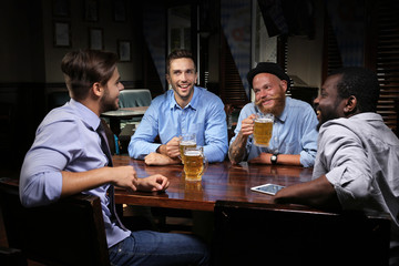 Obraz na płótnie Canvas Young men drinking beer and talking in cafe