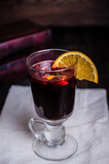 A glass of mulled wine and a slice of orange is on the table