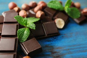 Chocolate pieces with nuts on color wooden background