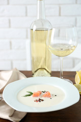 Served wooden table with tasty salmon cream soup, wine and lemon on it, close up