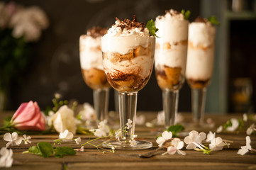 Delicious creamy dessert in a glass on a table strewn with flower petals