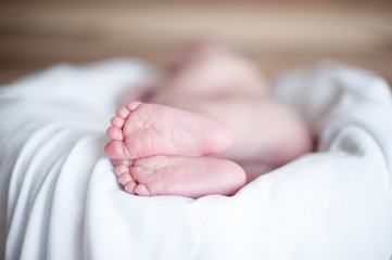 Small legs of the child, who is sleeping on a white sheet