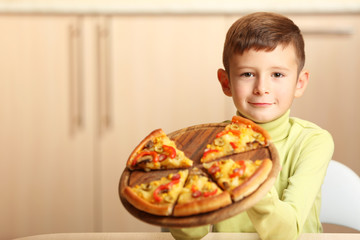 Little boy eating pizza at home