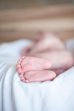Small legs of the child, who is sleeping on a white sheet