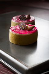 individual raspberry pistachio tarts topped with almond and chocolate turquoise background