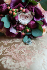 Bridal bouquet and two wedding rings lie on the couch