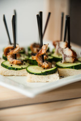 Snack on white bread with fried shrimp and cucumber on a skewer