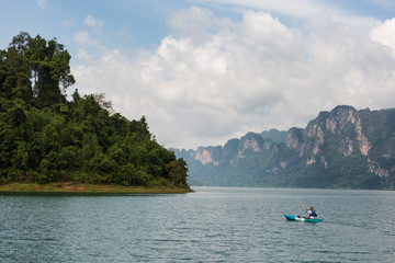 Fototapeta na wymiar man kayaking in the sea with lime stone mountain