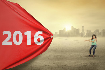Woman dragging red flag with numbers 2016