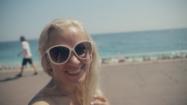 Happy girl in sunglasses takes selfie while walking along the French Riviera in Nice