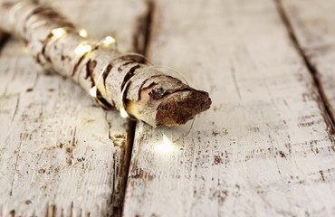 old tree log with fairy christmas lights on wooden table.selective focus.
