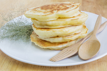 Pancakes and small white flowers on wooden background