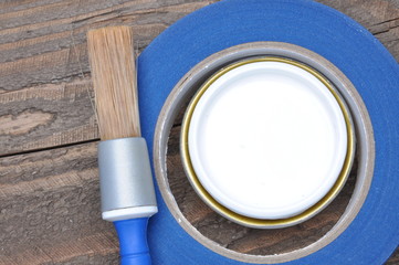 Can of white paint brush and masking tape on old boards