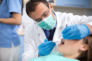 Dentist with protective mask and gloves repair tooth of his clie