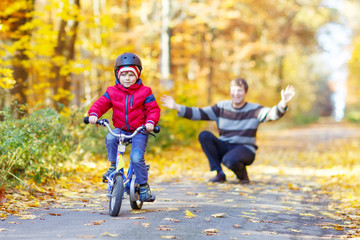 Fototapeta premium Little kid boy and father with bicycle in autumn forest