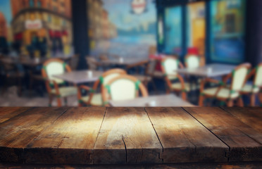 image of wooden table in front of abstract blurred background of restaurant lights