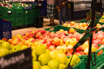 Bunch of red and green apples on boxes in supermarket