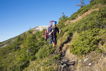 Fototapeta premium Two girls with backpacks walk along a trail.