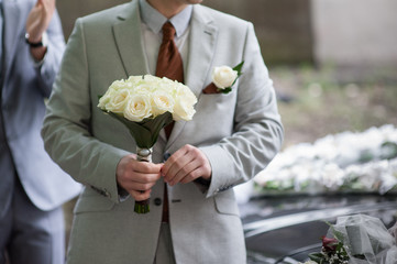 groom holding a wedding bouquet of white roses - Powered by Adobe
