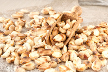 Heap of roasted peeled dry peanuts on wooden plank. Closeup.
