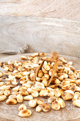 Heap of roasted peeled dry peanuts on wooden plank. Closeup.