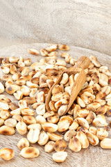 Heap of roasted peeled dry peanuts on wooden plank. Closeup.