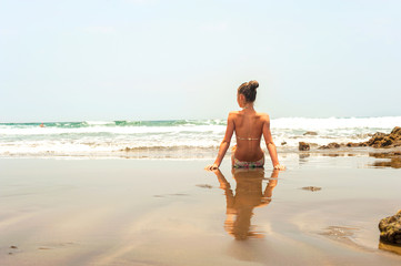 Young teenage girl sitting on the beach of Atlantic ocean.