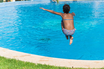 Brazilian girl jumping in tropical blue swimming pool in summer - 96397175