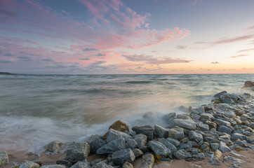 Baltic sea coast at sunset, with granite groyne in Rowy, near Ustka, Poland
