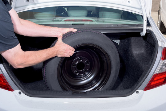 Man Pulls Spare Tire From Trunk Of Car