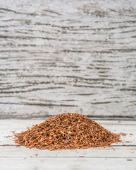 Dried rooibos herbal tea over wooden background