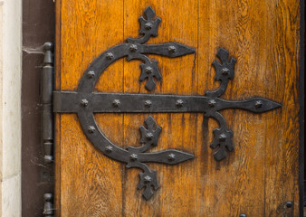 Ancient wooden door with decorative hinge forged in steel