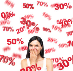 A portrait of a happy brunette lady in a white tank top who is dreaming about discounts. Red percentage marks are flying around the lady on white background.