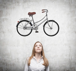 A beautiful girl in formal clothes is dreaming about a new bicycle. A sketch of a bicycle is drawn...