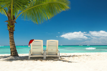 Santa's hat and sun loungers on the tropical beach © ValentinValkov