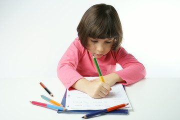 little girl is doing homework on a white background, dressing a pink shirt
