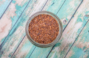 Obraz na płótnie Canvas Dried rooibos herbal tea leaves in mason jar over wooden background