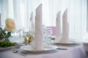 Serving festive table with plates and forks. Linen napkins on the table. Festive food. Serving of food. Cold snacks. Dish of food. Menu for a person. Food for anniversaries, weddings and celebrations.