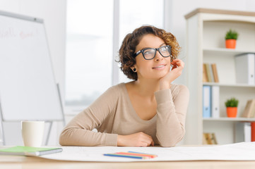 Young female stuff member sitting at the working desk.